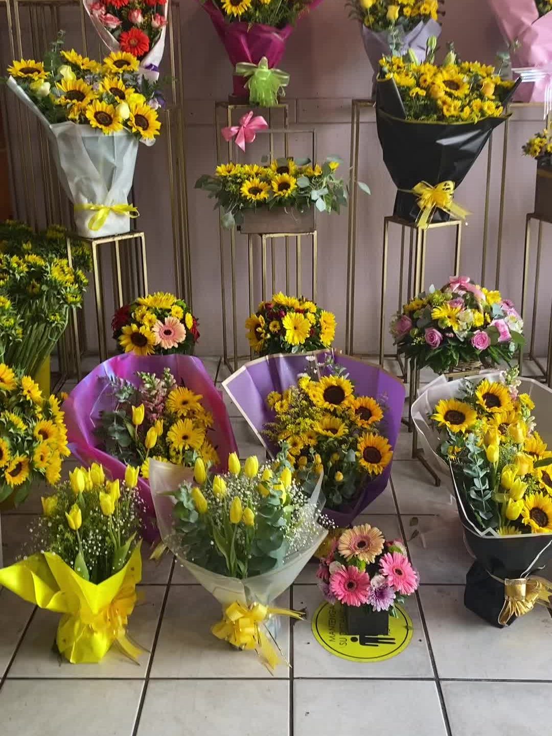 Exhibidor de la florería con ramos de girasoles, tulipanes amarillos y gerberas